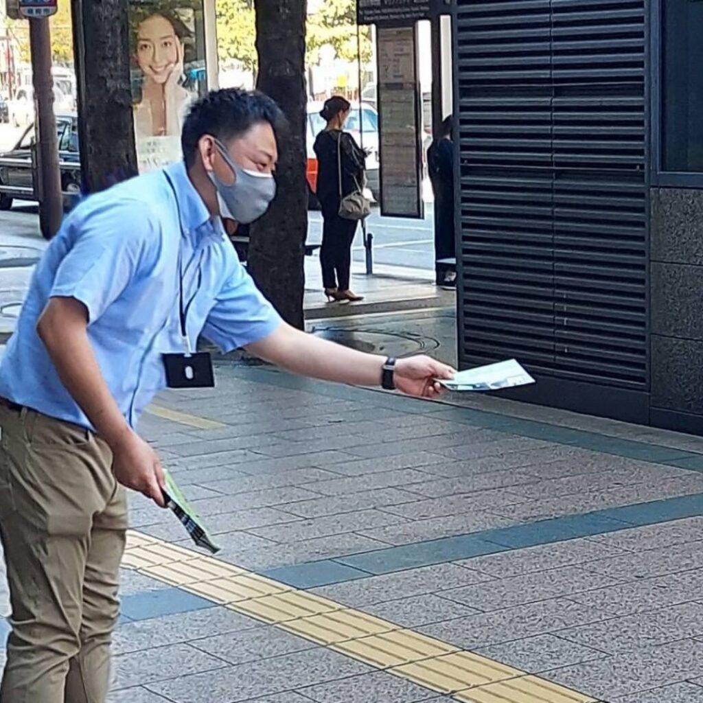 笑顔でチラシ配布する男性