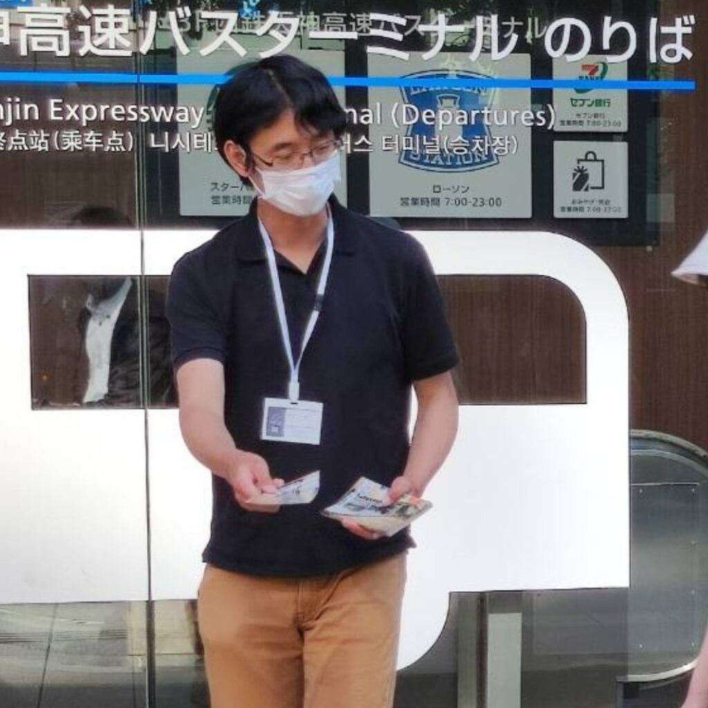 細身の男性がチラシを配っている光景